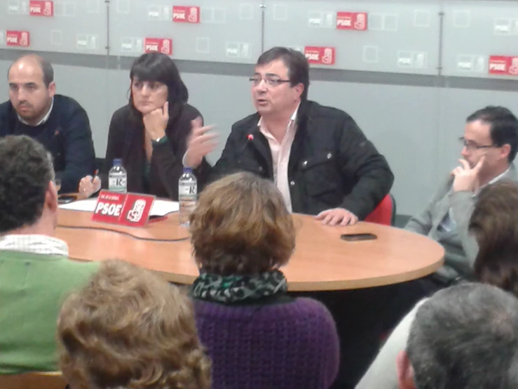 four men and two women sitting at a round table