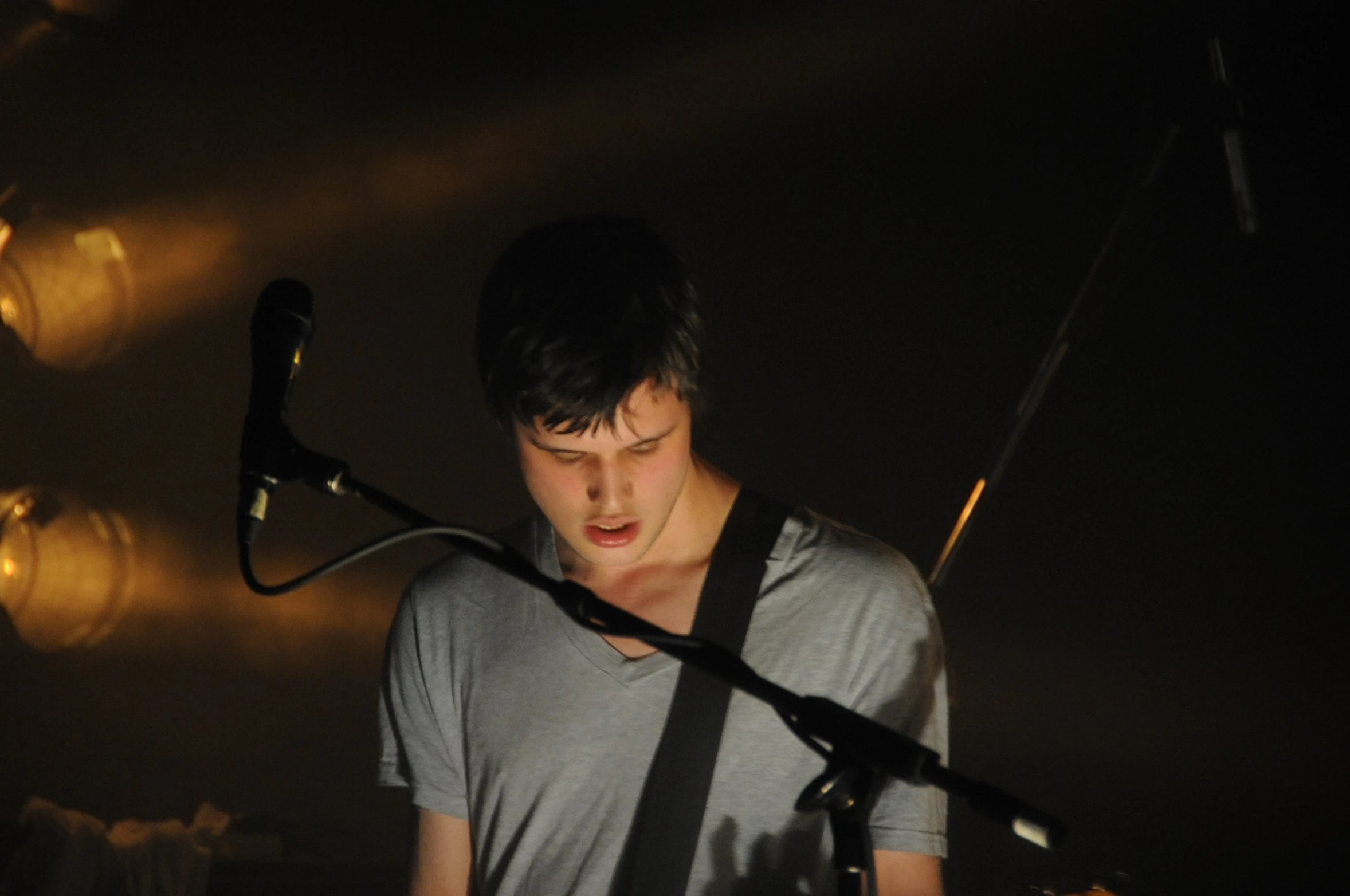 a young man with a guitar standing by an empty mic