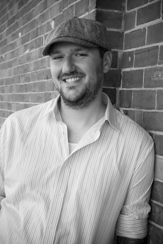 black and white pograph of smiling man with baseball cap on