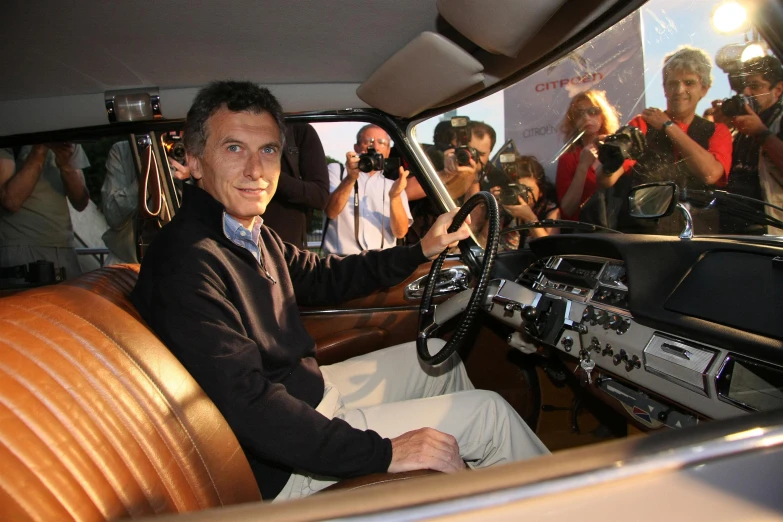 a man in a car with people around him and on the ground