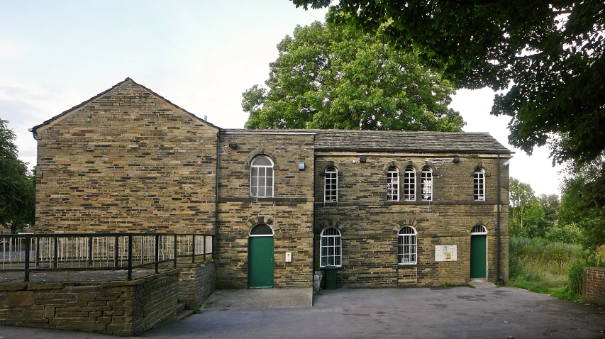 a brown brick building surrounded by trees and fencing