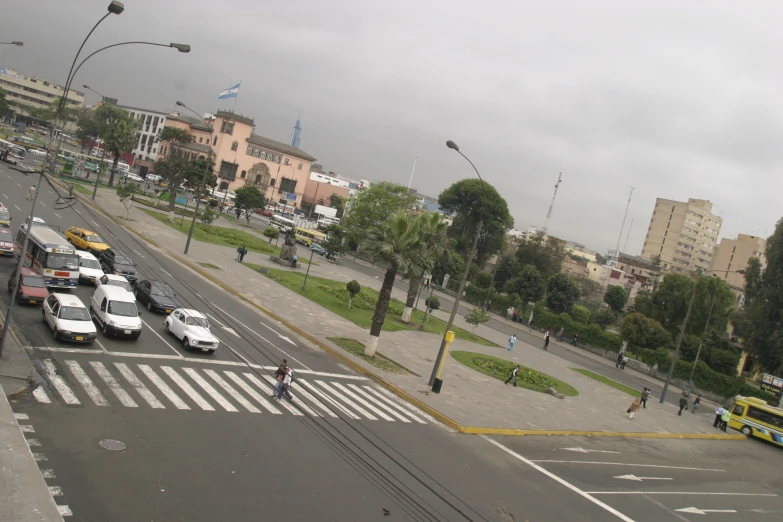 an intersection with traffic and pedestrians on a cloudy day