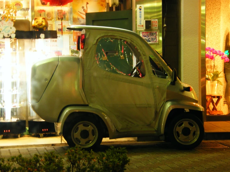 an old green little car sits on the curb