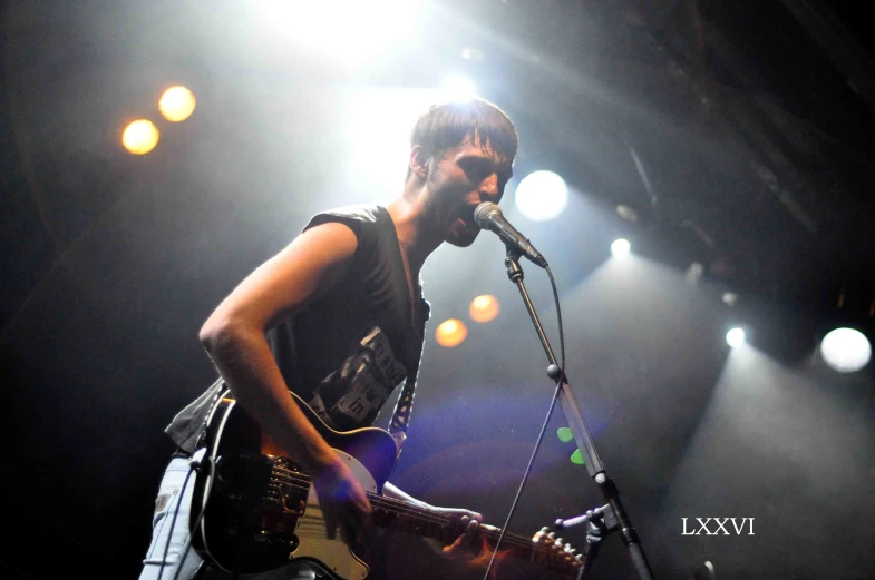 a man playing guitar and singing into the microphone