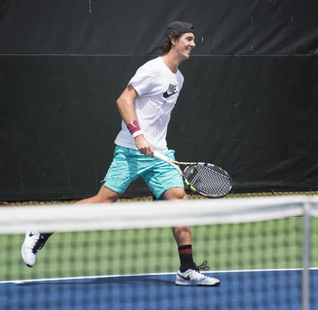 a young man on a tennis court swinging his racket