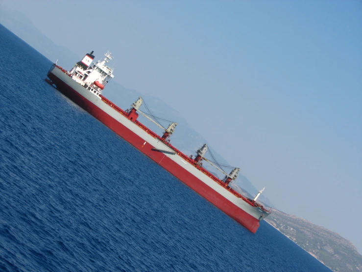 a red and white cargo ship floating on the ocean