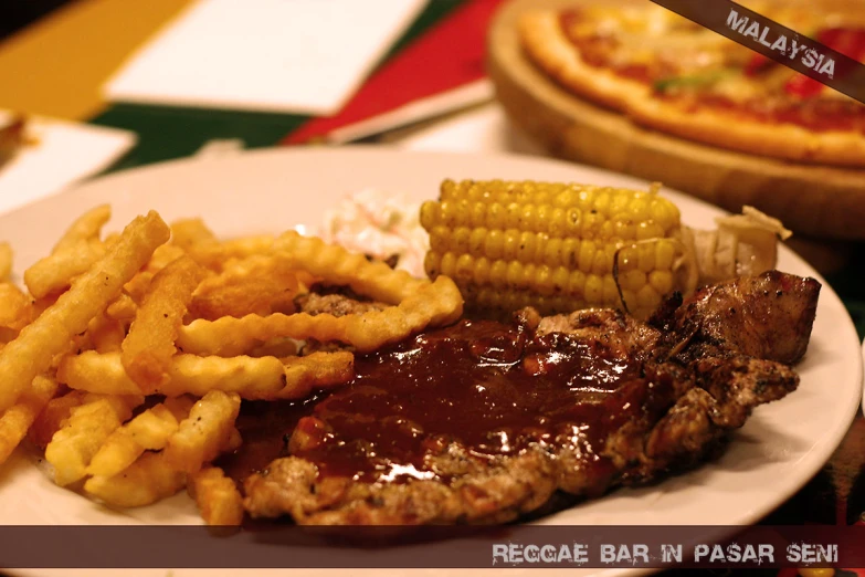 a white plate topped with steak, corn and french fries