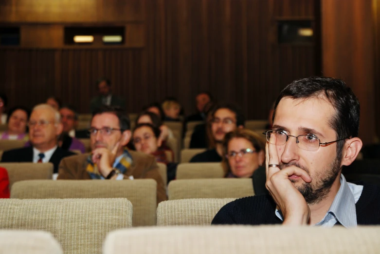 there is a man with glasses in front of an audience