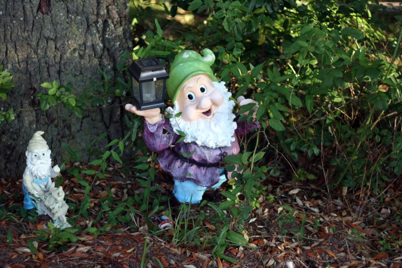 a small garden statue of a gnome in the woods with a dog and a camera