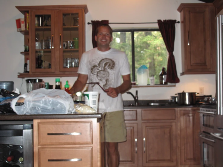 a man standing in a kitchen holding a piece of wood