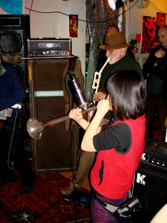 a woman in a red shirt and two men are standing around a room