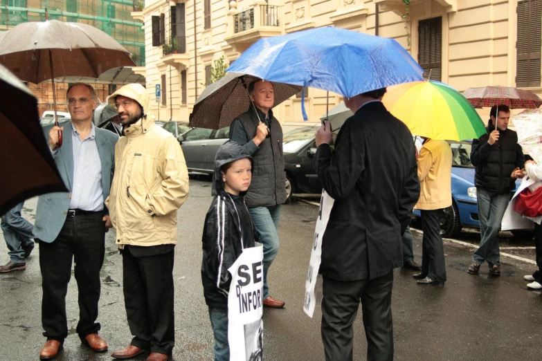 several people and one man hold umbrellas in the street