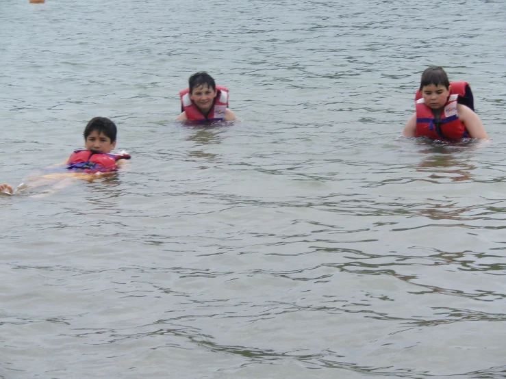 three children float in the water and play