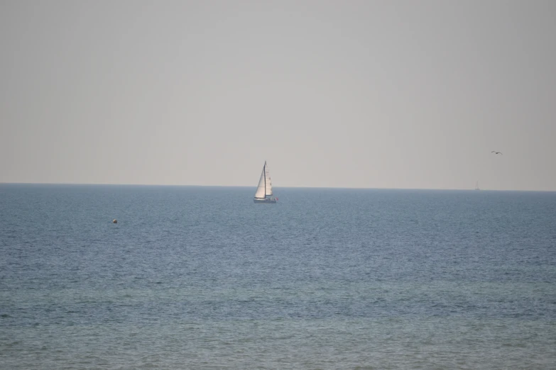 a sailboat floats in the water next to some rocks