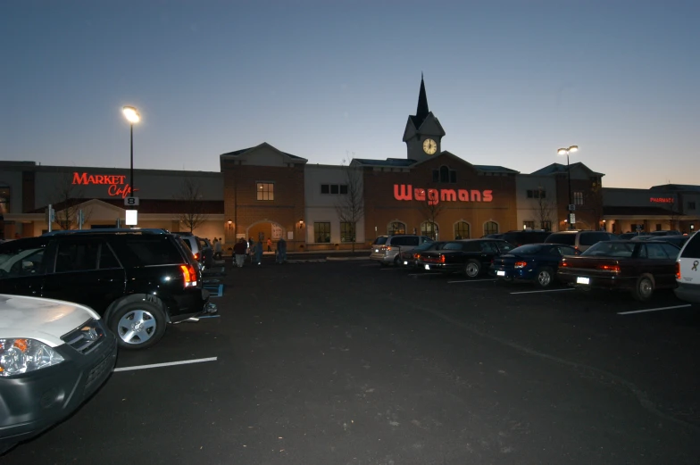 many cars are parked in front of a building at dusk