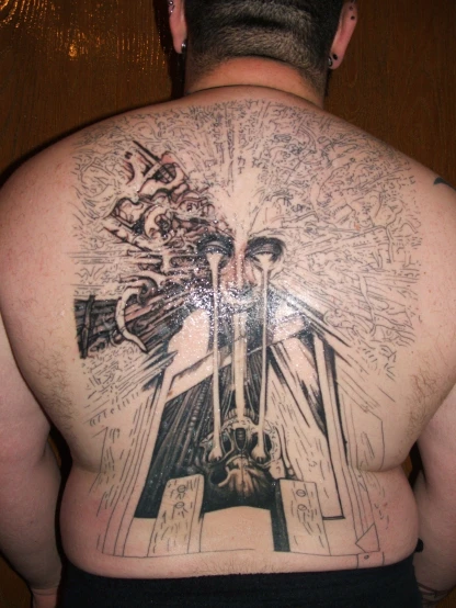 a man wearing a religious back tattoo with symbols