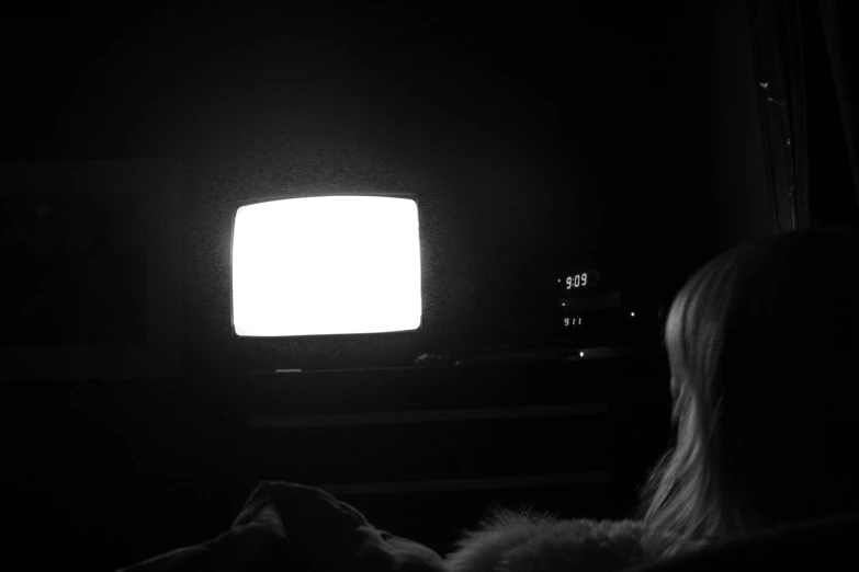 a girl in a dark room watching television