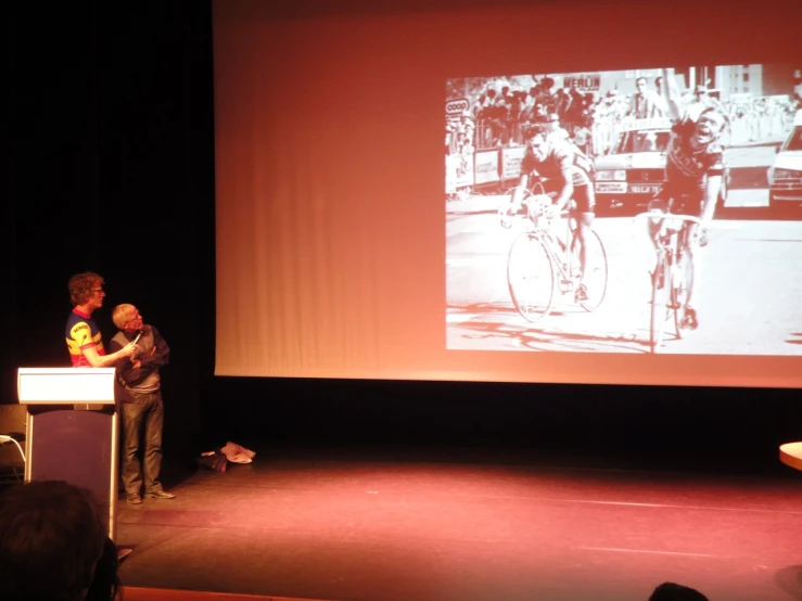 a man stands behind a podium in front of a projection