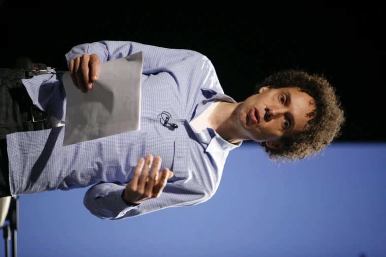 a man speaking into a microphone while holding a tablet