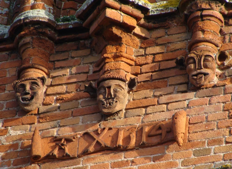 several heads are on the side of a brick building