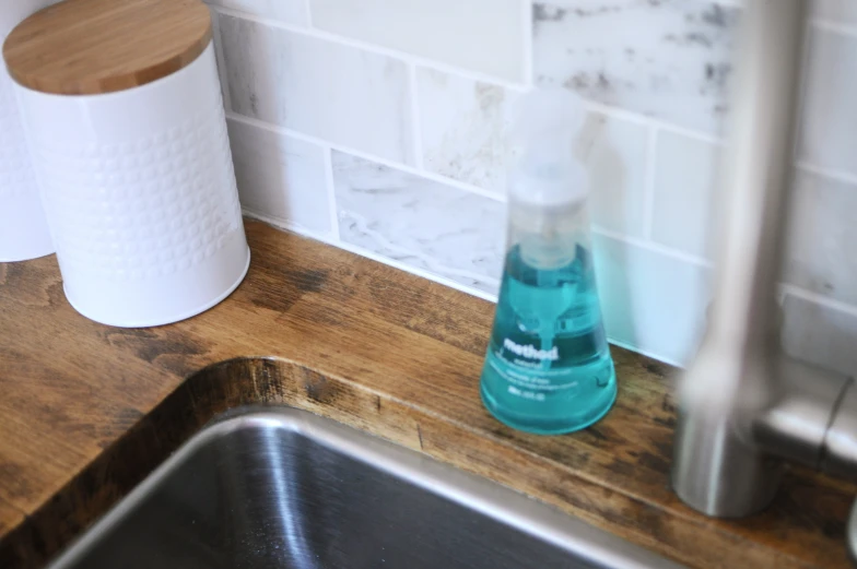 a closeup of a blue bottle of hand sanitizer next to a sink and a counter