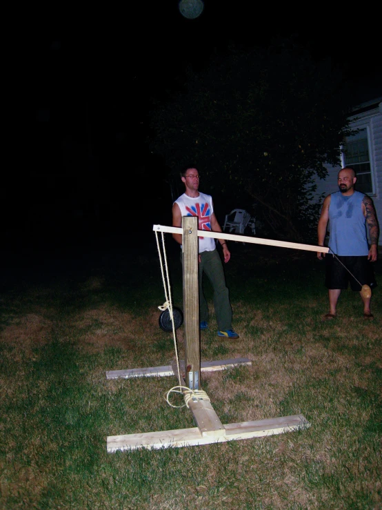 two men standing outside at night holding on to two different poles