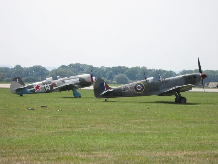 three small airplanes are parked on some grass