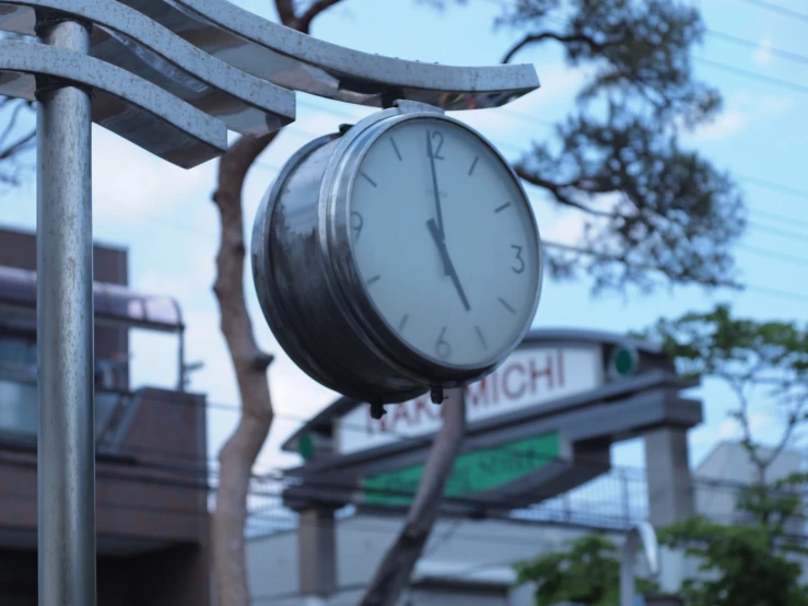 a clock hanging outside next to a tree