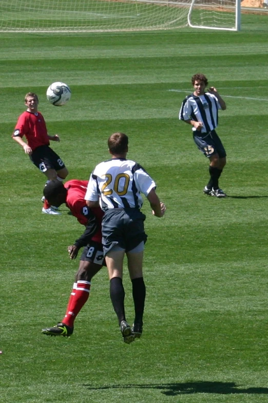 three soccer players chase the ball while another passes them