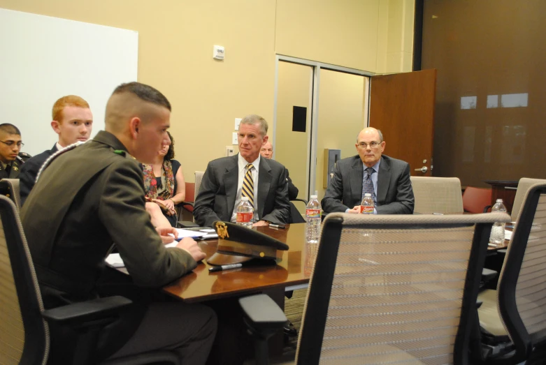 a group of men sitting at a table in front of a computer