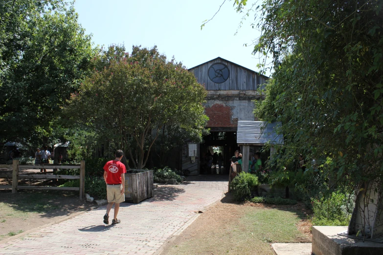 a man walking down a pathway in front of a small shed