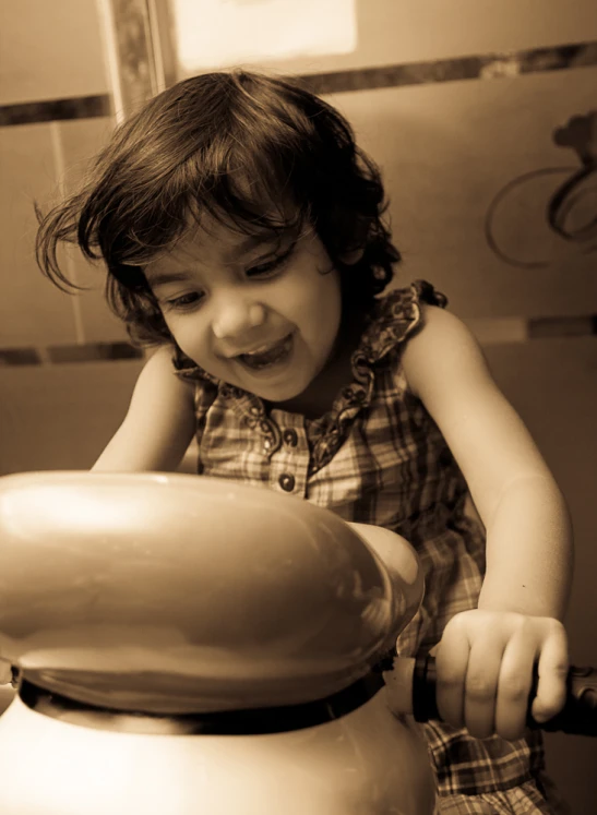 a small child in a dress pouring soing in a big pitcher