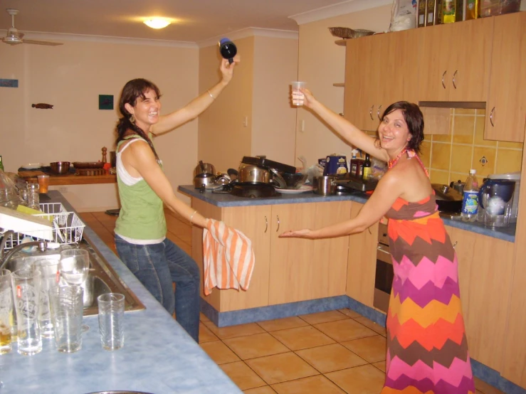 two women in a kitchen giving each other the finger