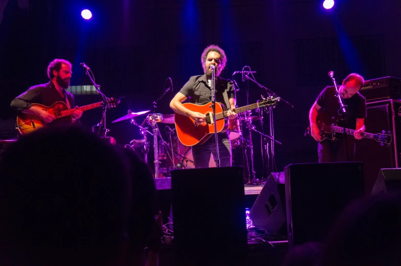 a group of people playing guitar and singing on stage