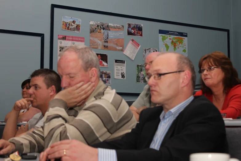 people in a group are sitting at a desk with papers