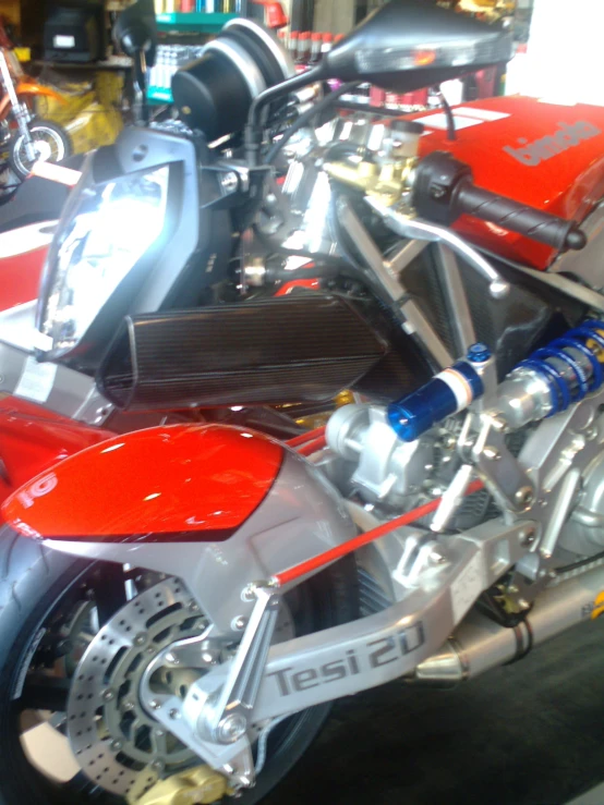 a red motorcycle sits in a shop near other motorcycles