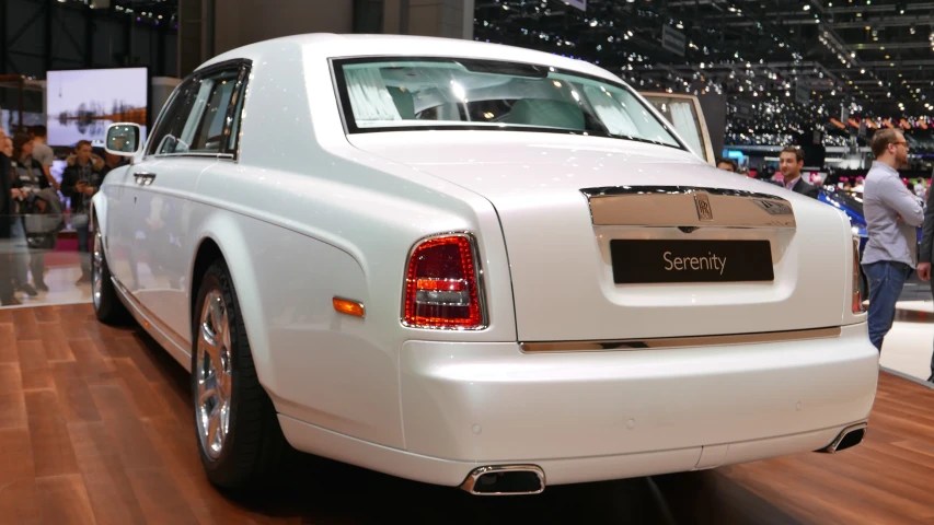 people look at some white rolls royce at an auto show