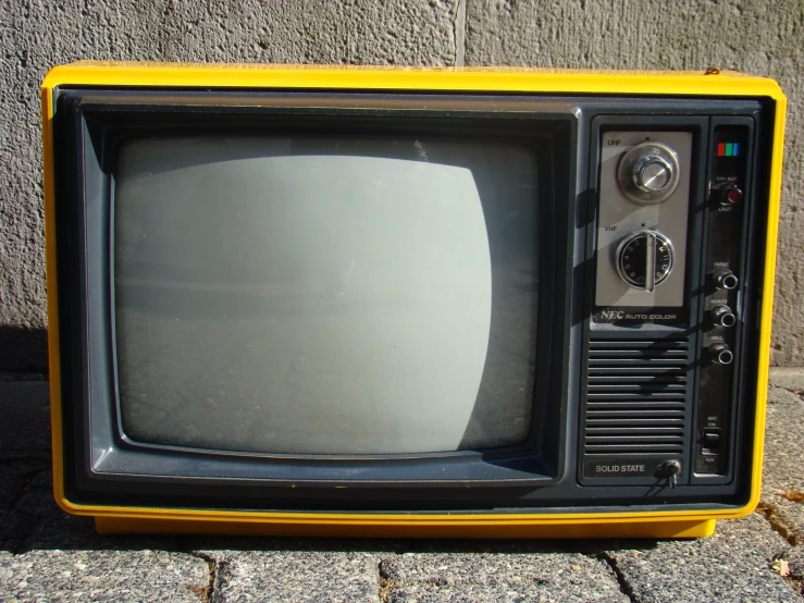 a small black television with yellow trim sitting outside