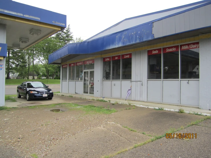 a car sits parked in front of the small shop