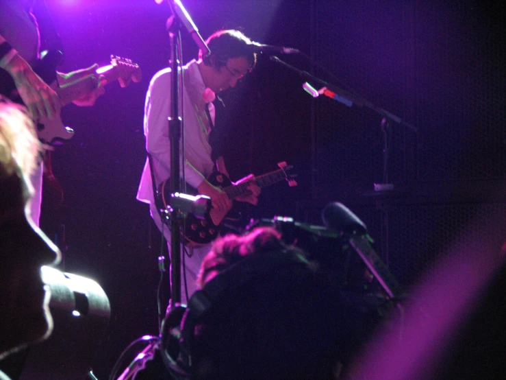 two people on stage with guitars and microphone