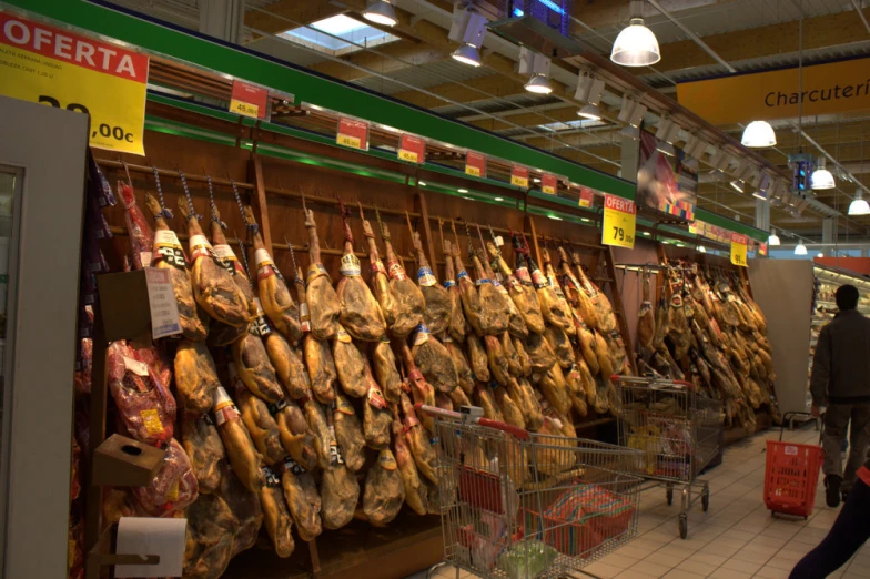 several large pieces of pork hang in the store