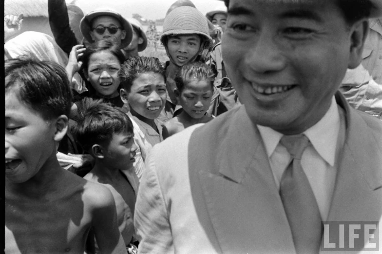 black and white pograph of smiling man amongst the small crowd