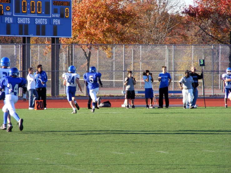 some players playing football and a large scoreboard with trees in the background