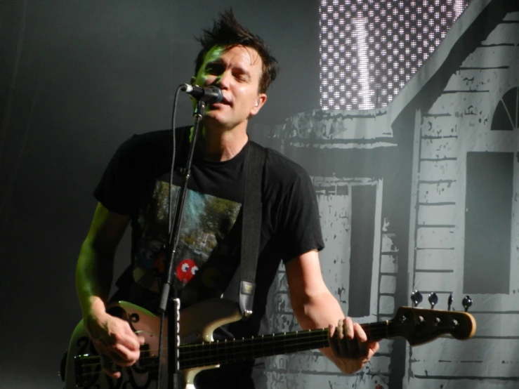 a young man with black hair on stage playing guitar