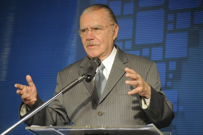 a man talking at a podium in front of a microphone