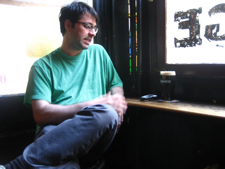 a man wearing glasses is sitting in front of a window