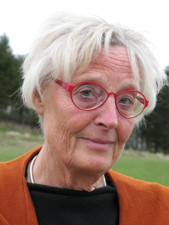 an older woman in red glasses wearing a brown cardigan