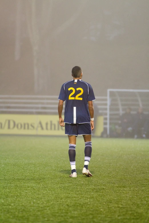 a young man standing on a soccer field wearing a jersey