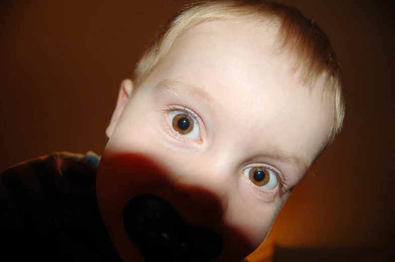 a close up of a child blowing in a persons nose