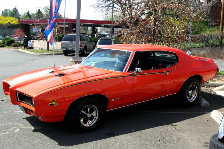 a very bright orange car is parked in the parking lot